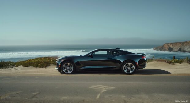 1080P Car Wallpaper HD with a sleek Camaro SS parked on a coastal road with waves crashing in the background.