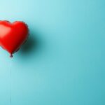 3D Heart shaped balloon floating in a sky blue background.