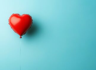 3D Heart shaped balloon floating in a sky blue background.