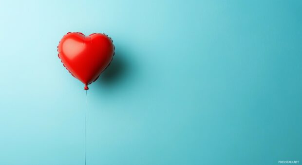 3D Heart shaped balloon floating in a sky blue background.