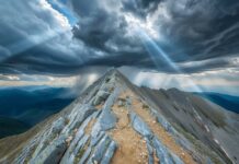 3D Nature with rocky mountain peak with dramatic clouds, sun breaking through, majestic view.