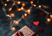 A Valentines gift box wrapped in red ribbon, surrounded by tiny heart confetti and soft fairy lights.