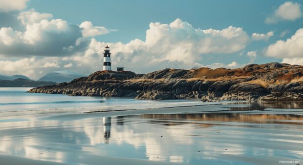 A beach 1080p Full HD Image with a lighthouse standing tall on a rocky promontory.