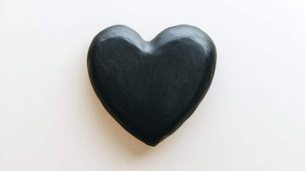 A bold, solid black heart centered on a soft white background, with a slight shadow effect to create depth and a modern, minimalist aesthetic.