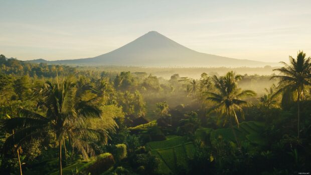 A breathtaking view of a volcanic mountain surrounded by lush tropical greenery and clear skies, 4K wallpaper.