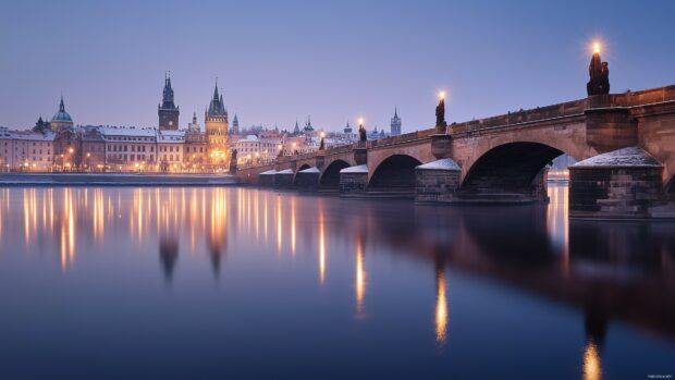 A city bridge spanning a river at twilight, with lights reflecting in the water below.