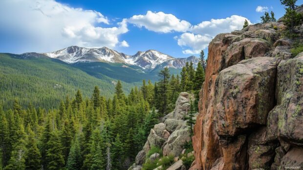 A close up of a rocky cliff face in the Rocky Mountains, with snow capped peaks in the background.