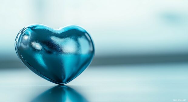 A close up of a shiny blue heart on a simple pastel background.