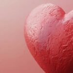 A close up of a textured heart on a muted pink background.