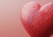 A close up of a textured heart on a muted pink background.