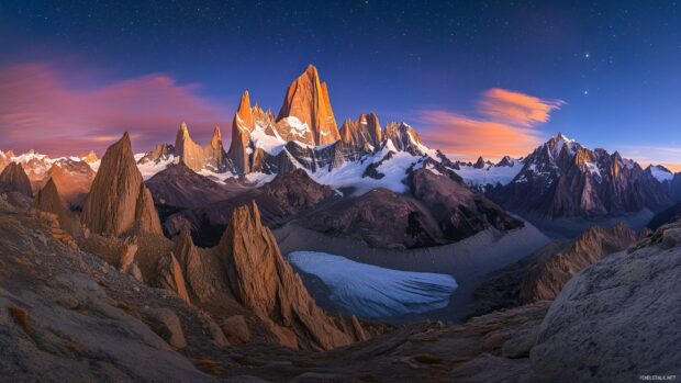 A cool mountain desktop wallpaper with sharp peaks under a vibrant starry night sky.