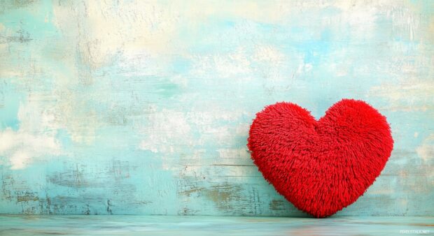 A large, plush red heart on a soft, pale blue background.