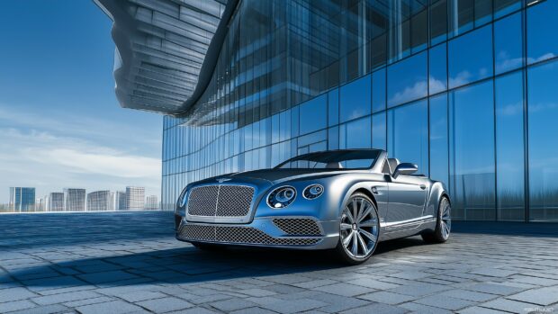 A luxury car parked in front of a modern glass building under a clear blue sky.