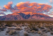 A majestic Mountain range glowing under the fiery hues of a sunset sky.