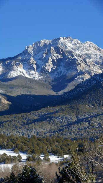 A majestic winter mountain range under a clear blue sky for phone wallpaper.