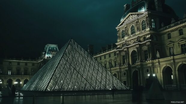 A nighttime shot of the Louvre Pyramid, glowing against the historic architecture of the museum.