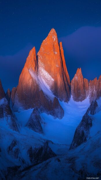 A panoramic view of jagged peaks illuminated by the soft light of the Milky Way.