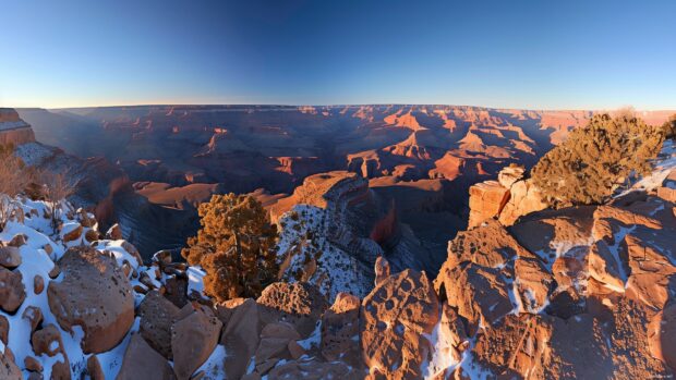 A panoramic view of the Grand Canyon with dramatic shadows and a clear sky.