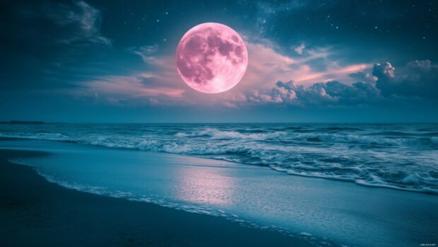 A pink moon partially hidden behind thin clouds, illuminating a quiet beach.