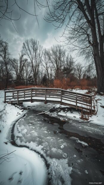 A quaint bridge crossing a frozen river in a winter setting.