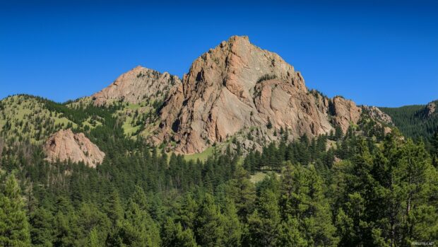 A rugged Rocky Mountain peak under a clear blue sky.