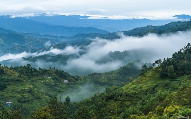 A scenic mountain panorama with rolling hills, misty valleys.