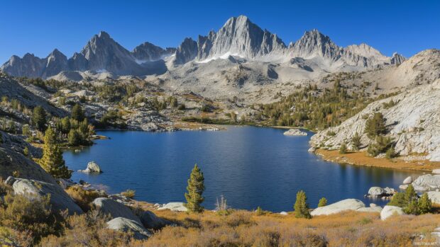 A serene blue Mountain lake surrounded by towering peaks under a clear sky.