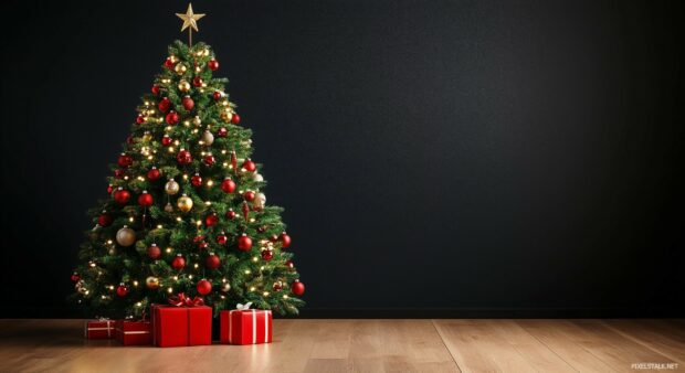 A small, tastefully decorated Christmas tree on a wooden floor.