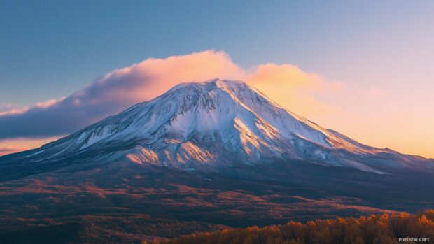 A snow covered mountain peak glowing under the golden hues of a sunrise.