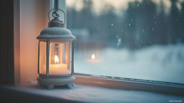 A soft, glowing Christmas lantern on a snowy windows.