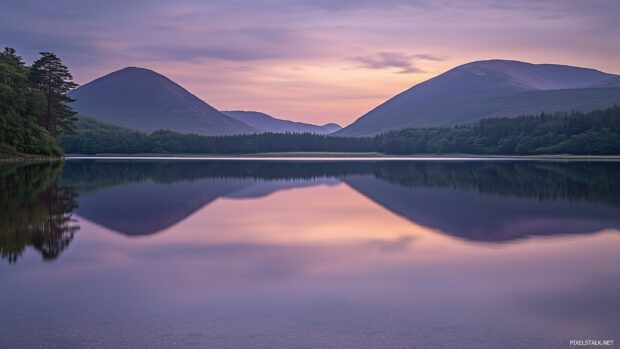 A tranquil Mountain lake mirroring the golden and purple hues of a sunset.