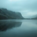 A tranquil lake surrounded by mountains at dawn with mist rising from the water, Backgrounds 1920×1080.