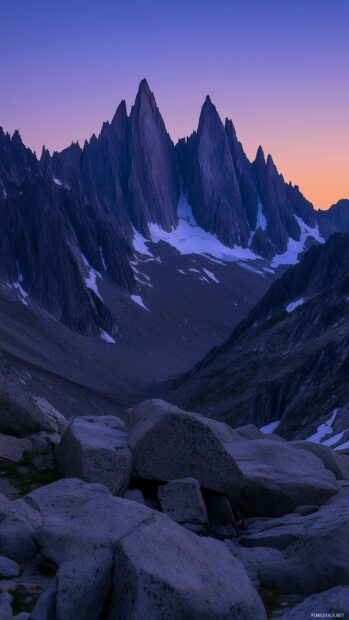 A tranquil mountain vista at twilight, with the peaks silhouetted against a gradient sky of deep blue and orange.