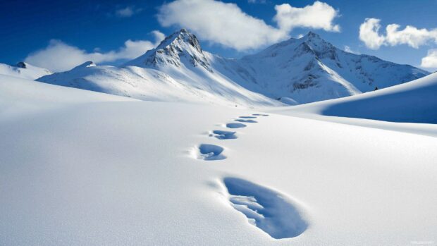 A tranquil snow mountain valley with footprints in the deep white snow.