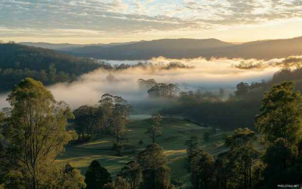 A view mountain landscape panorama with rolling hills, misty valleys, and sunlight breaking through the clouds.