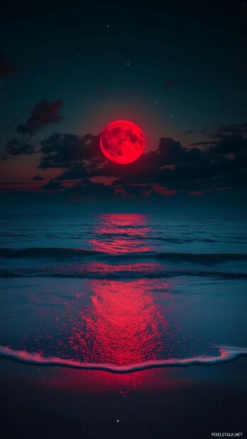 Aesthetic Moon Wallpaper with a mesmerizing red moon hanging low in the night sky over a tranquil beach.