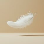 Amazing Laptop Wallpaper with a lone white feather floating in mid air on a beige background, exuding simplicity and elegance.