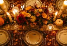 An elegant Thanksgiving table setting featuring a fall themed tablecloth and a centerpiece with seasonal flowers and pumpkins.