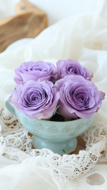 An elegant composition of purple roses arranged artistically in a vintage teacup, surrounded by delicate lace and soft fabrics.