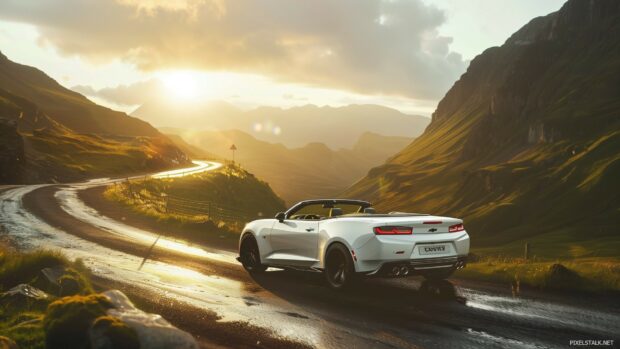 Car Desktop Wallpaper with with a Camaro convertible cruising through a scenic mountain pass during sunset.