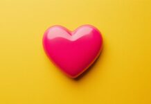 Flat heart valentine in bright pink on a simple yellow background.