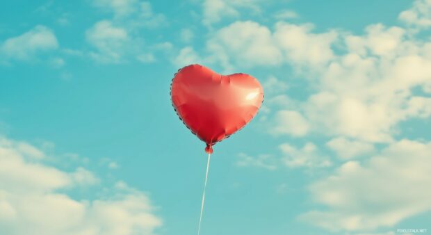 Heart shaped balloon floating in a sky blue background.