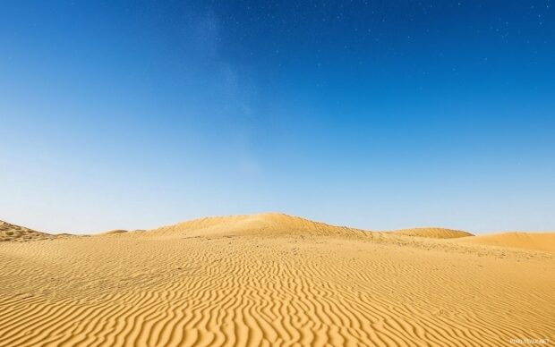 Majestic desert dunes under a clear night sky filled with stars, a peaceful and minimalist landscape.