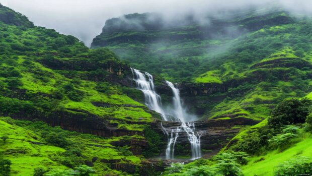 Majestic waterfall cascading down a lush green cliff, surrounded by mist and vibrant foliage.