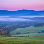 Misty blue Mountains stretching into the horizon under a soft pastel sky.