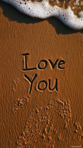 Nature Love Wallpaper with a beautiful hand drawn Love You written in the sand on a beach, with waves gently approaching in the background.