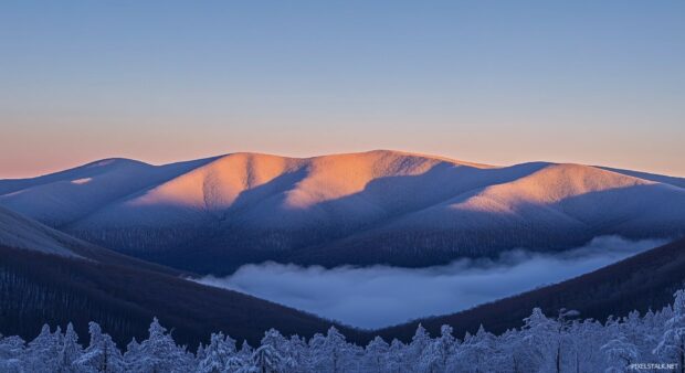 Snowy Mountain peaks illuminated by the soft, glowing amber of a setting sun.