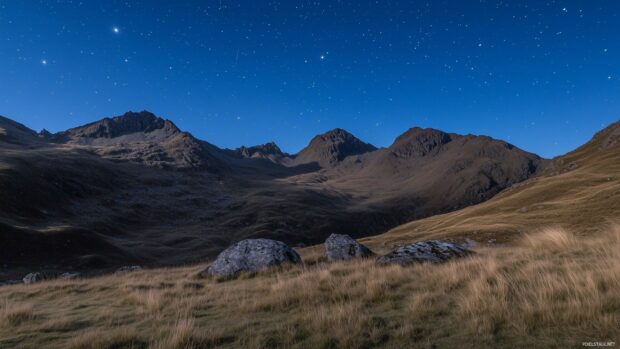 The moon and stars glowing gently over a quiet mountain range.