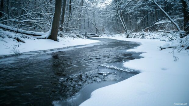 Winter stream with ice forming along the edges and a snowy backdrop, PC desktop wallpaper.