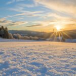 Winter sunrise casting a warm glow over snow covered fields.